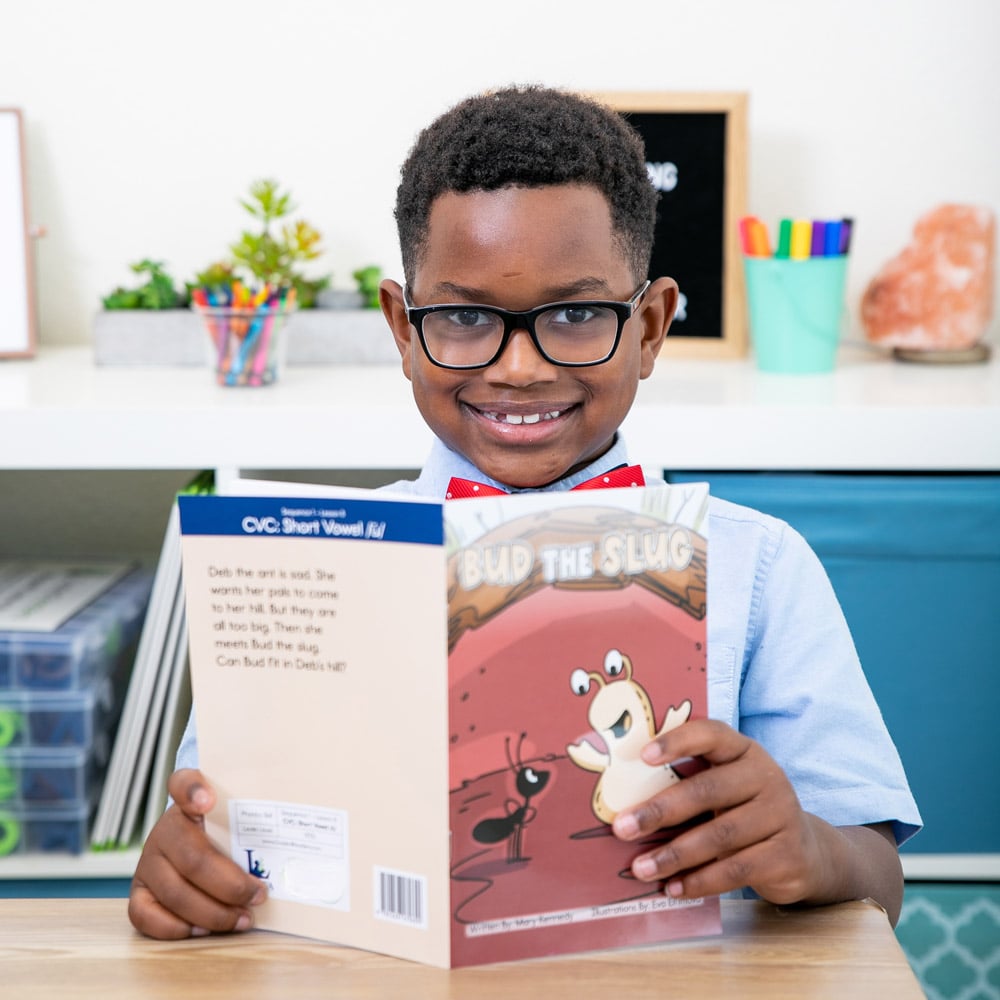 school-aged child reading a book at his desk at school